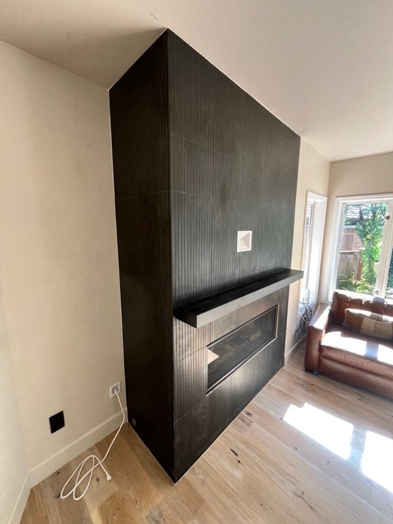 The black fluted fireplace column in the living room with wood floors