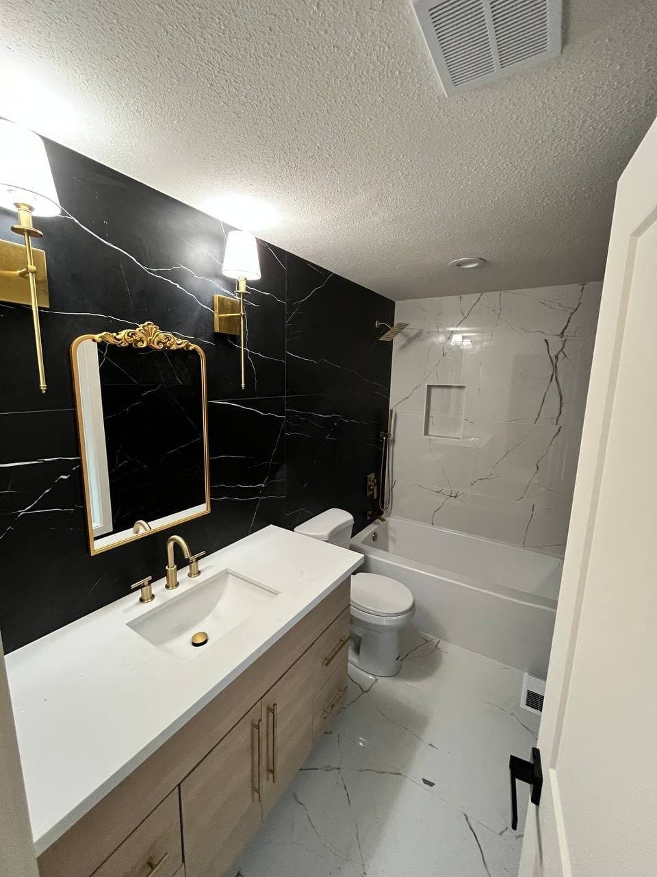 Bathroom with black marble-look porcelain feature wall and brass fixtures