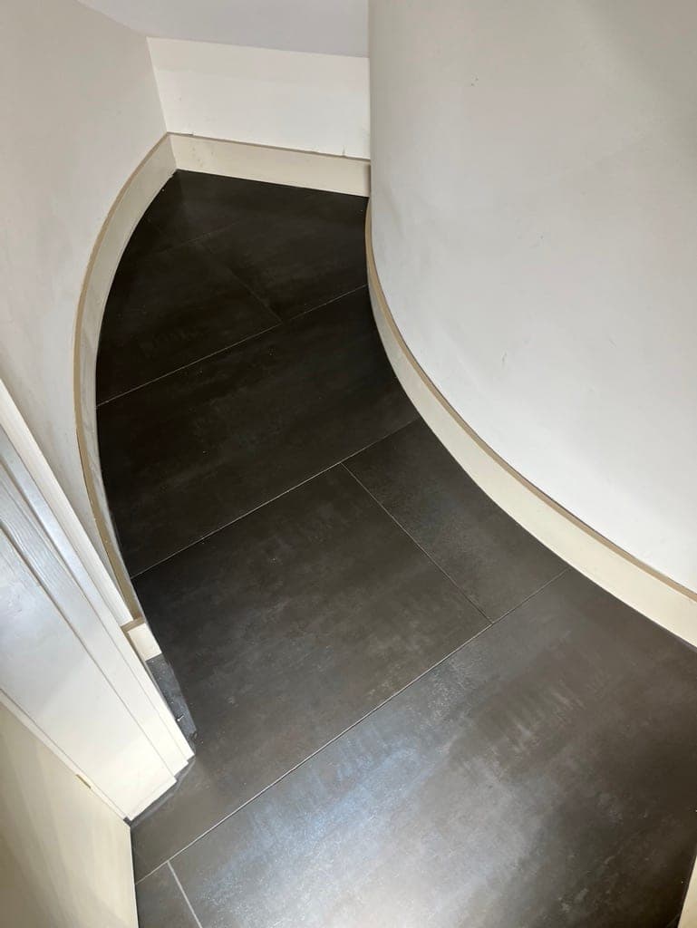 Charcoal floor tile cut to follow a curved hallway wall