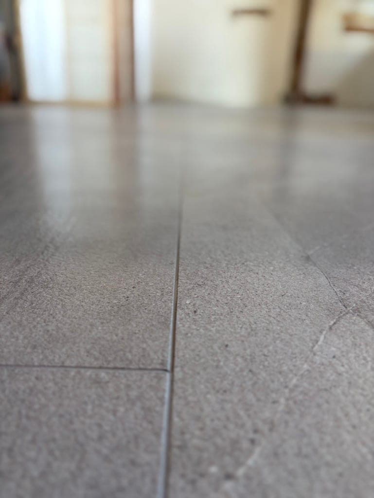 Close-up of a tight, flush grout joint between two large-format floor tiles