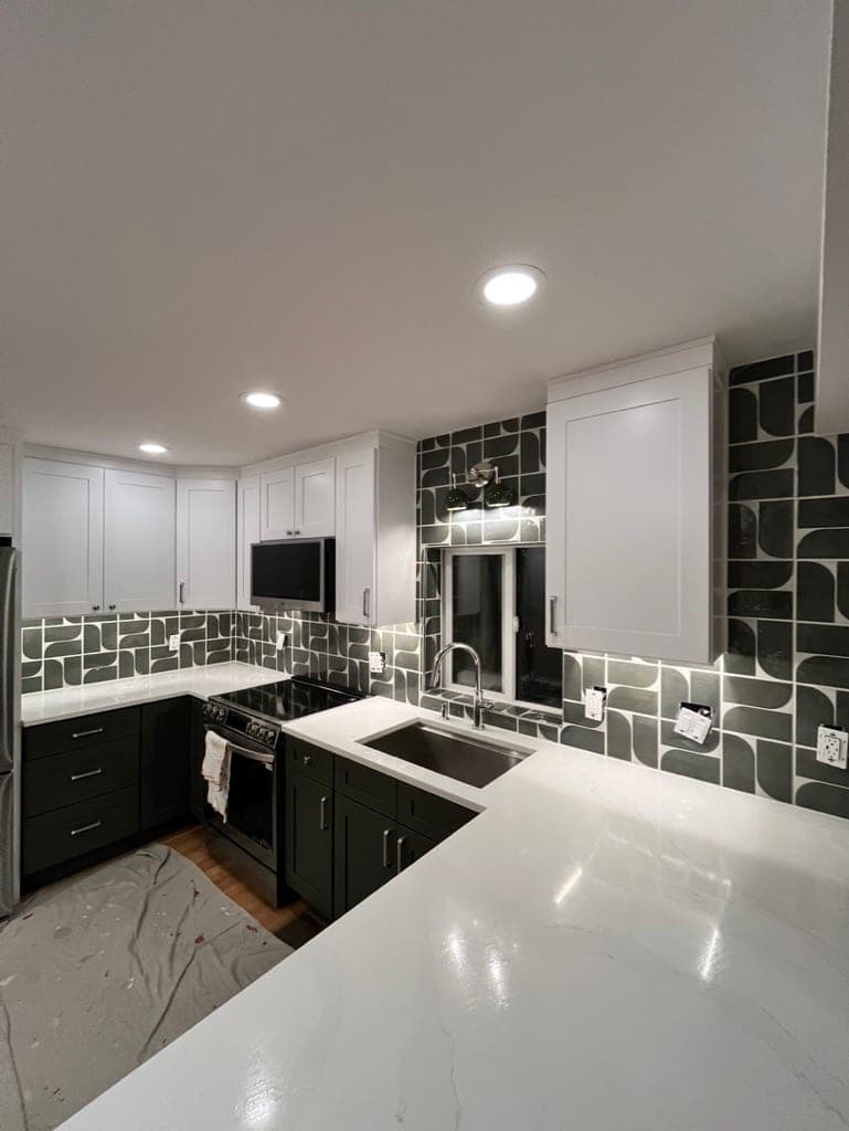 Kitchen with dark green ogee tile backsplash, white uppers, and dark lower cabinets