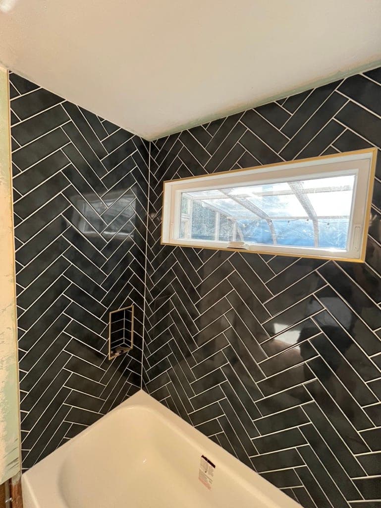 Corner of the herringbone tub surround showing the window return and tub edge