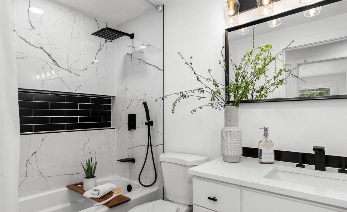 Finished tub surround in white marble-look porcelain with a black subway tile niche