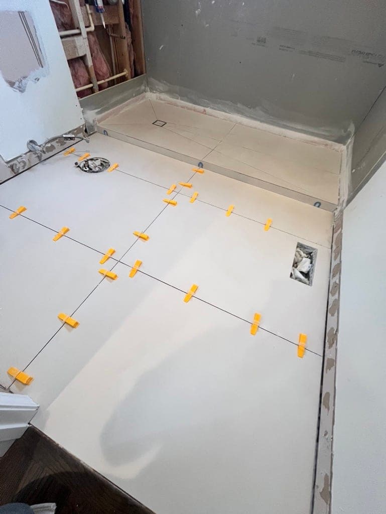 Bathroom floor tile with leveling clips set up to the shower curb