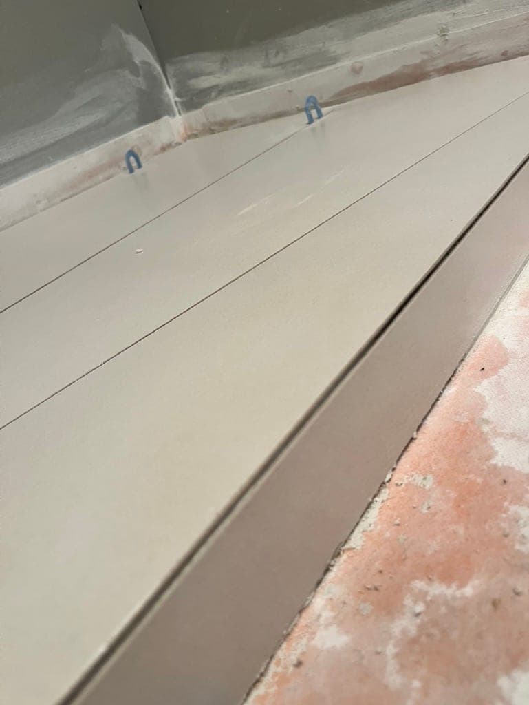 Concrete-look tile on a shower curb held with leveling clips