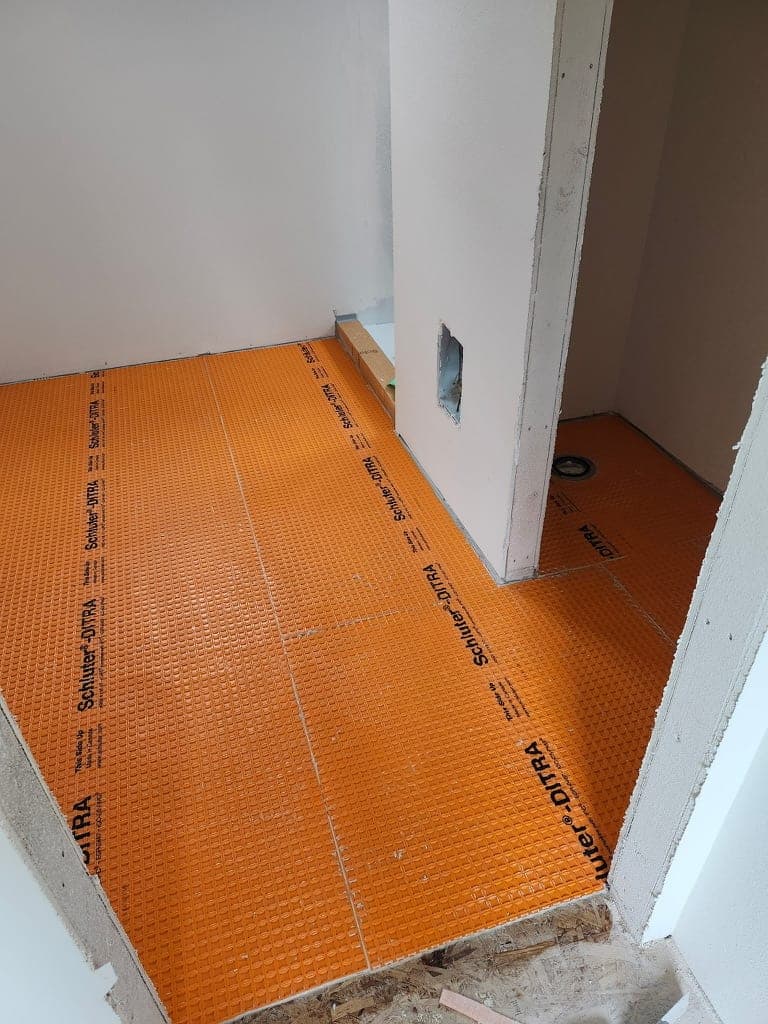 Orange uncoupling membrane installed across a floor before tile