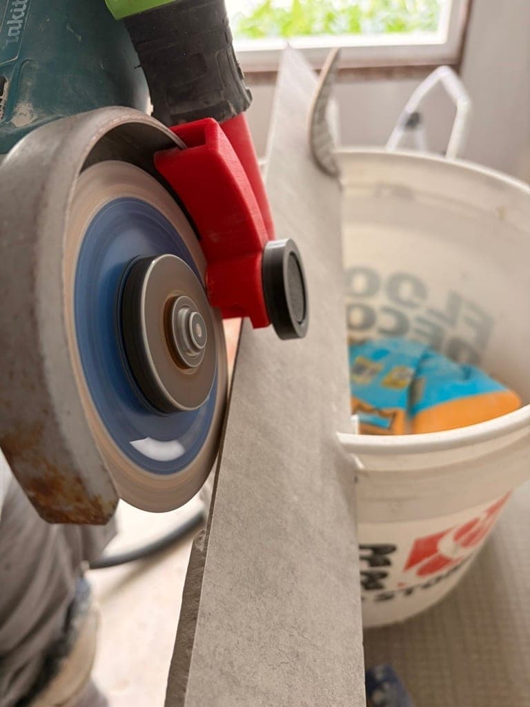 Angle grinder with a diamond blade cutting a large-format tile