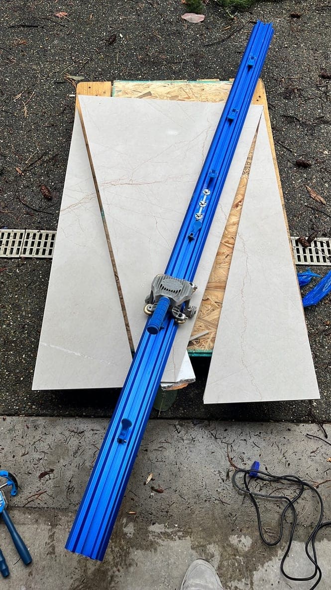 Rail cutter clamped to a porcelain slab for a straight cut