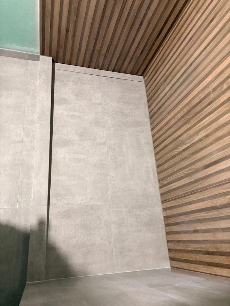 Corner where the slat tile meets the concrete-look large-format wall