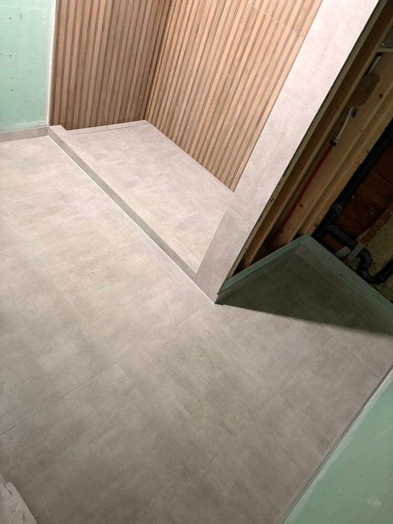 Concrete-look shower curb and floor looking out toward the bathroom