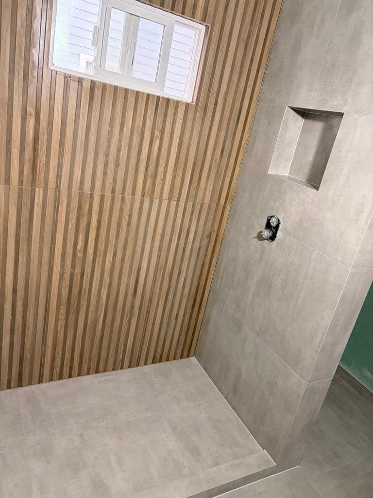 Shower niche cut into the wood-look slat wall with a window above