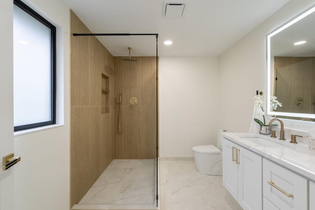 Walk-in shower in vertical wood-look slat porcelain with a brass rain head and single glass panel