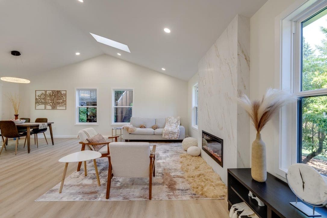 Living room with a marble-look porcelain fireplace wall next to the dining area