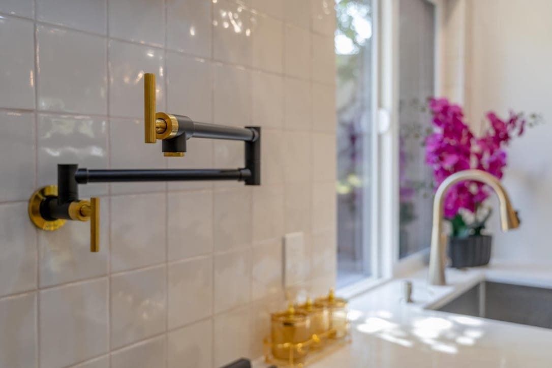 Detail of the pot filler and square tile with the sink and window beyond