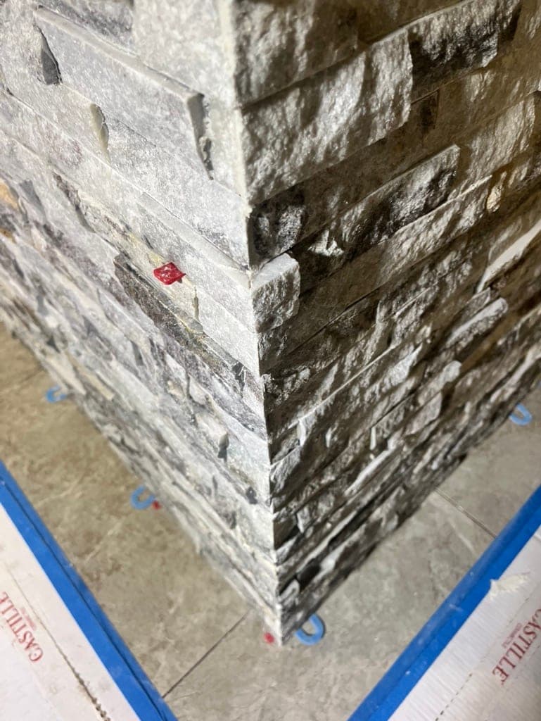 Outside corner of a stacked-stone wall mid-install with interlocking courses